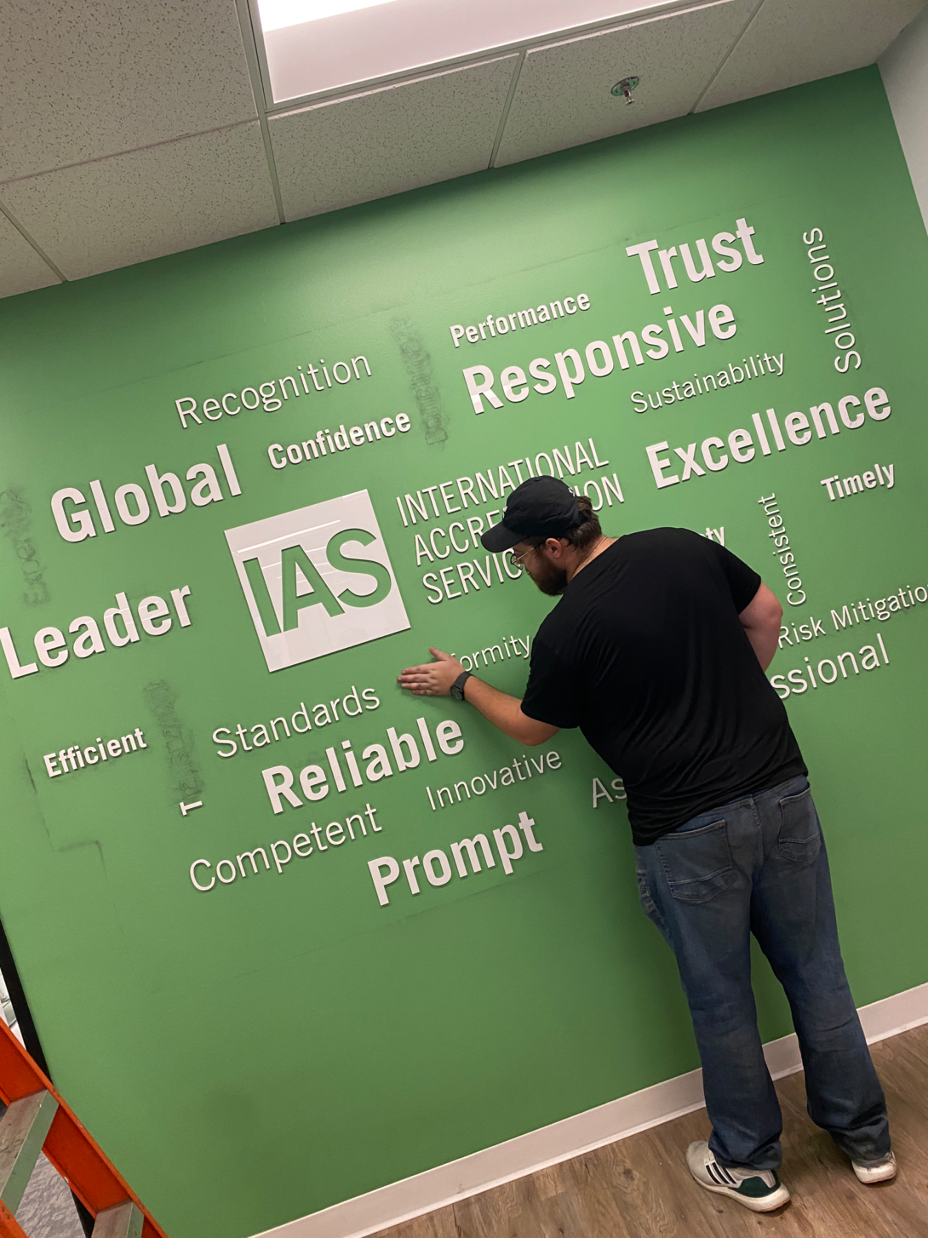 Hi Sign installer squeegeeing cut-vinyl word-cloud lettering onto a green office wall in Brea, CA