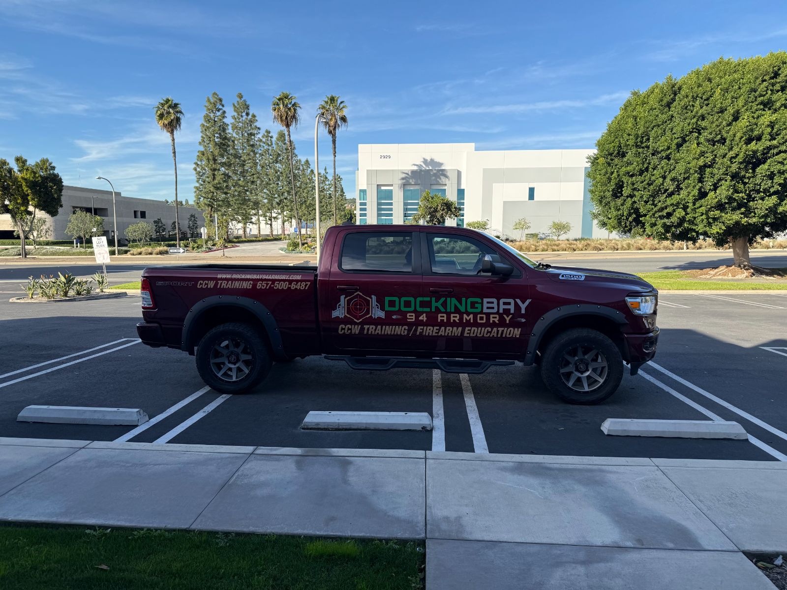 Driver side of a maroon Ram pickup with Docking Bay 94 Armory graphics: cast vinyl logo, 'CCW Training / Firearm Education' lettering, website and phone number across the cab and bed