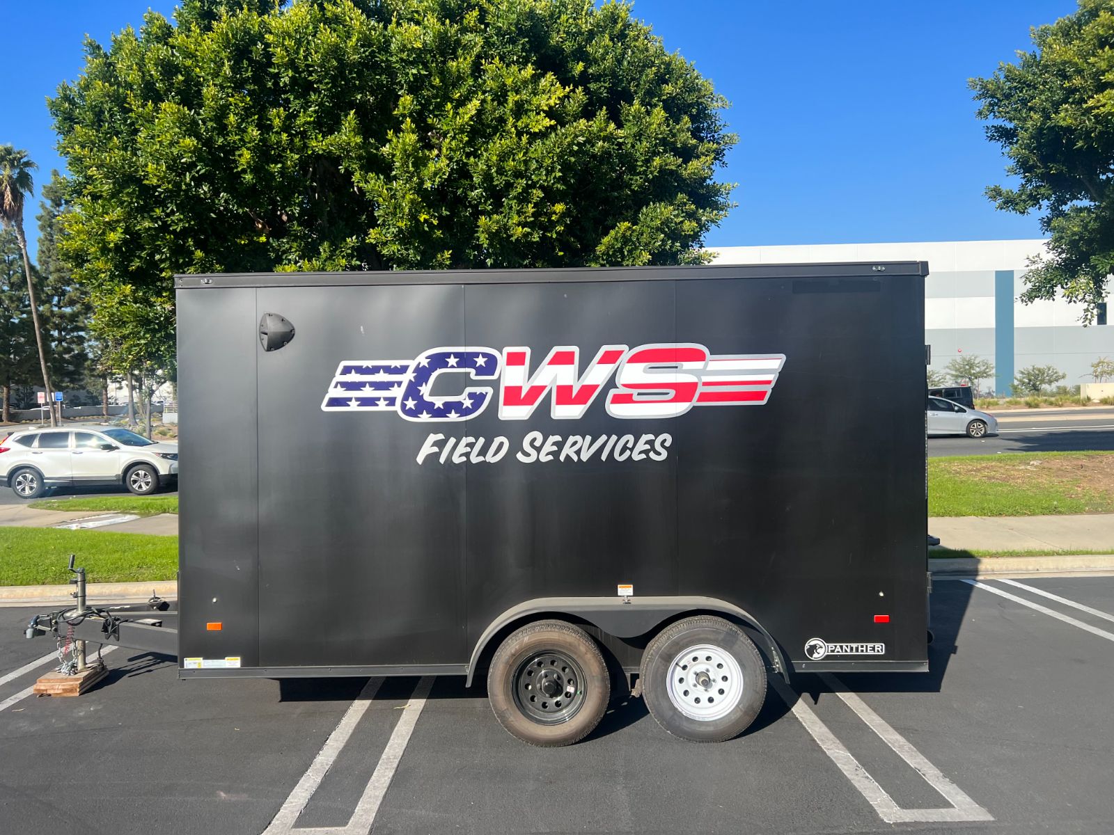 Side of a black CWS enclosed cargo trailer: stars-and-stripes 'CWS Field Services' vinyl logo and lettering across the panel