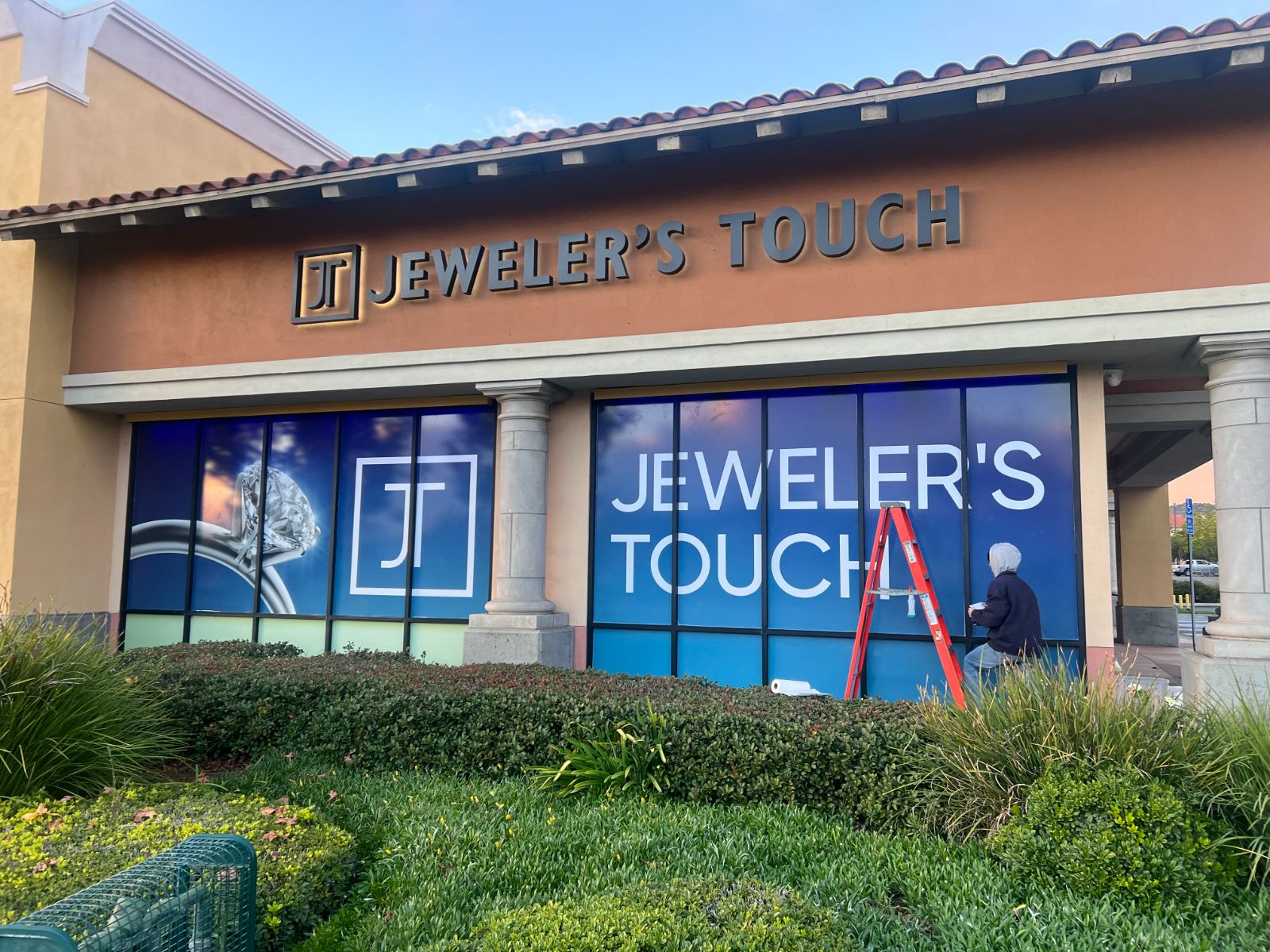 Jeweler's Touch storefront with dimensional letters and windows fully covered in blue printed vinyl graphics
