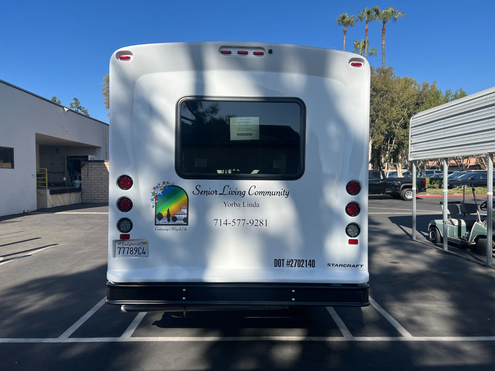 Rear of the same Starcraft shuttle bus: vinyl lettering, rainbow star logo, phone number, and DOT number applied to the rear body panel