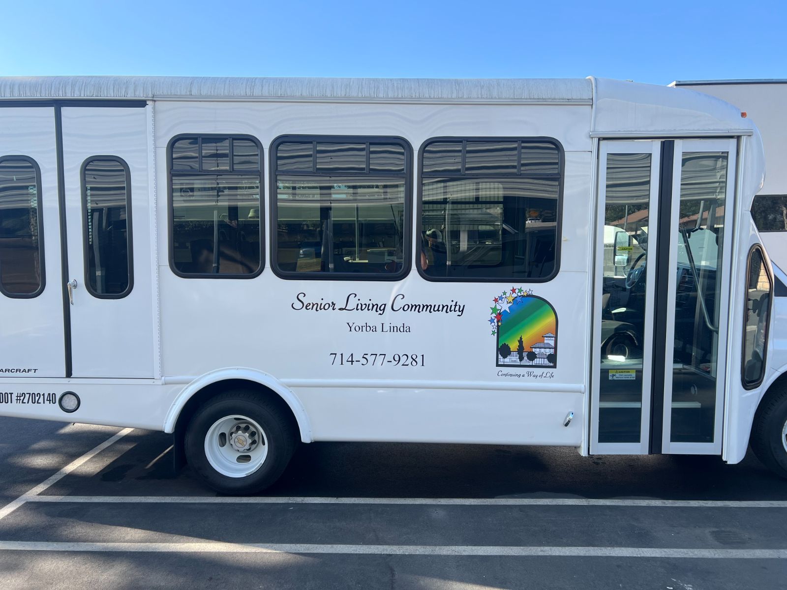 Passenger-side vehicle graphics on the same Starcraft shuttle bus: vinyl die-cut logo and cut lettering with business name, city, and phone number applied to the exterior body panel