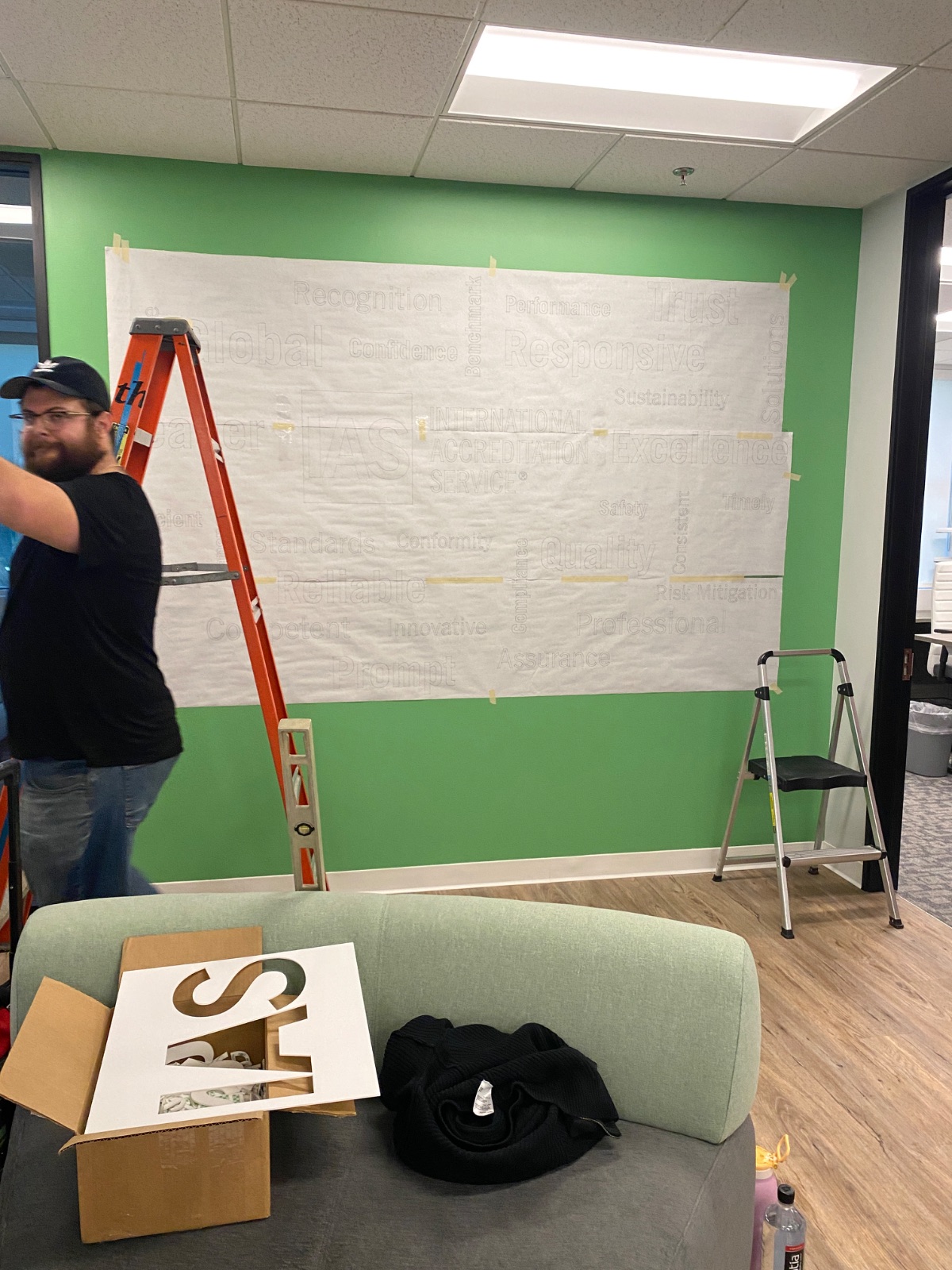 Install in progress: application tape masking the upper wall while the vinyl is positioned from a ladder