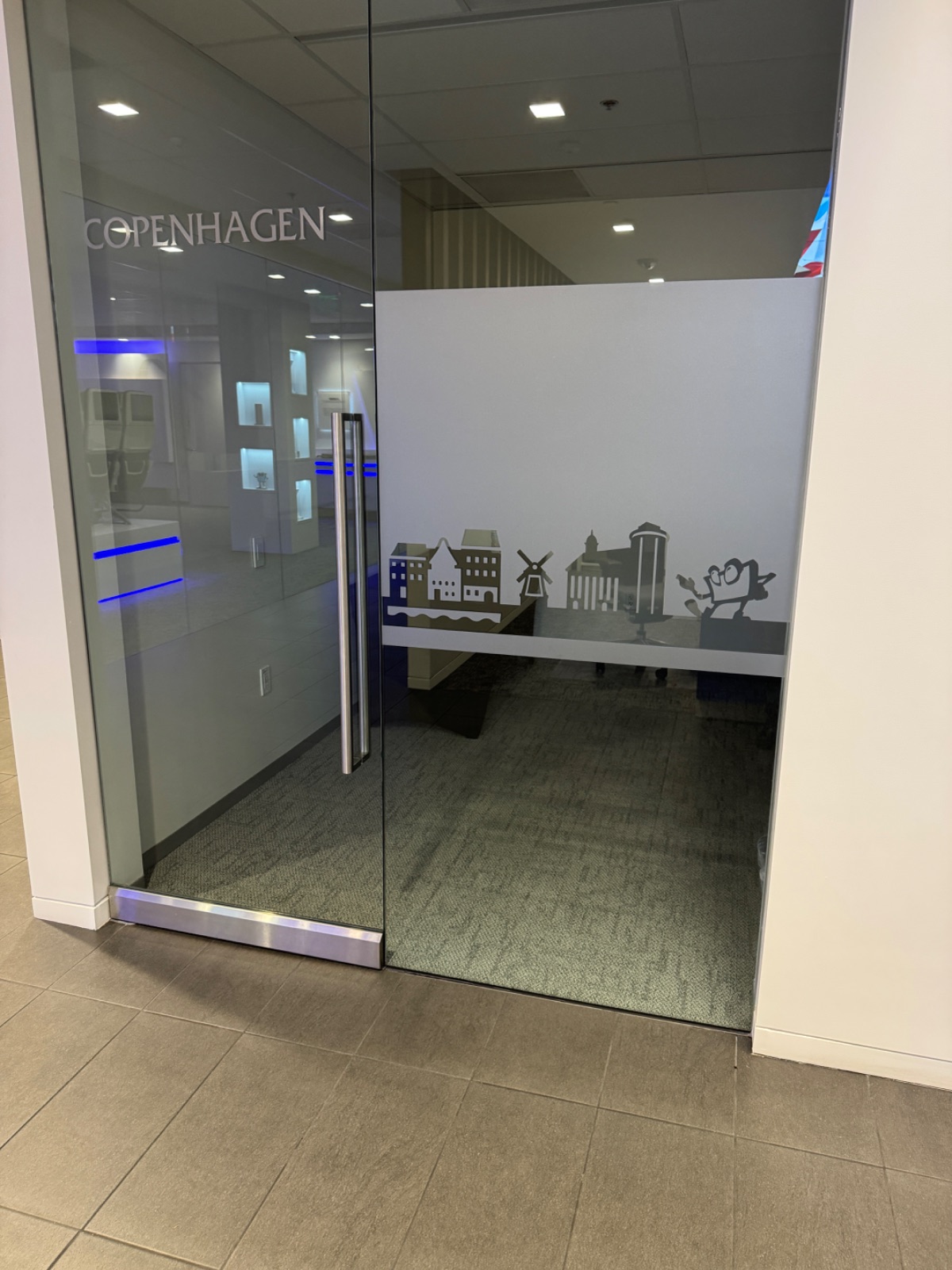 Angled view of the frosted glass room front, showing the Copenhagen skyline graphic and room name across two glass panels