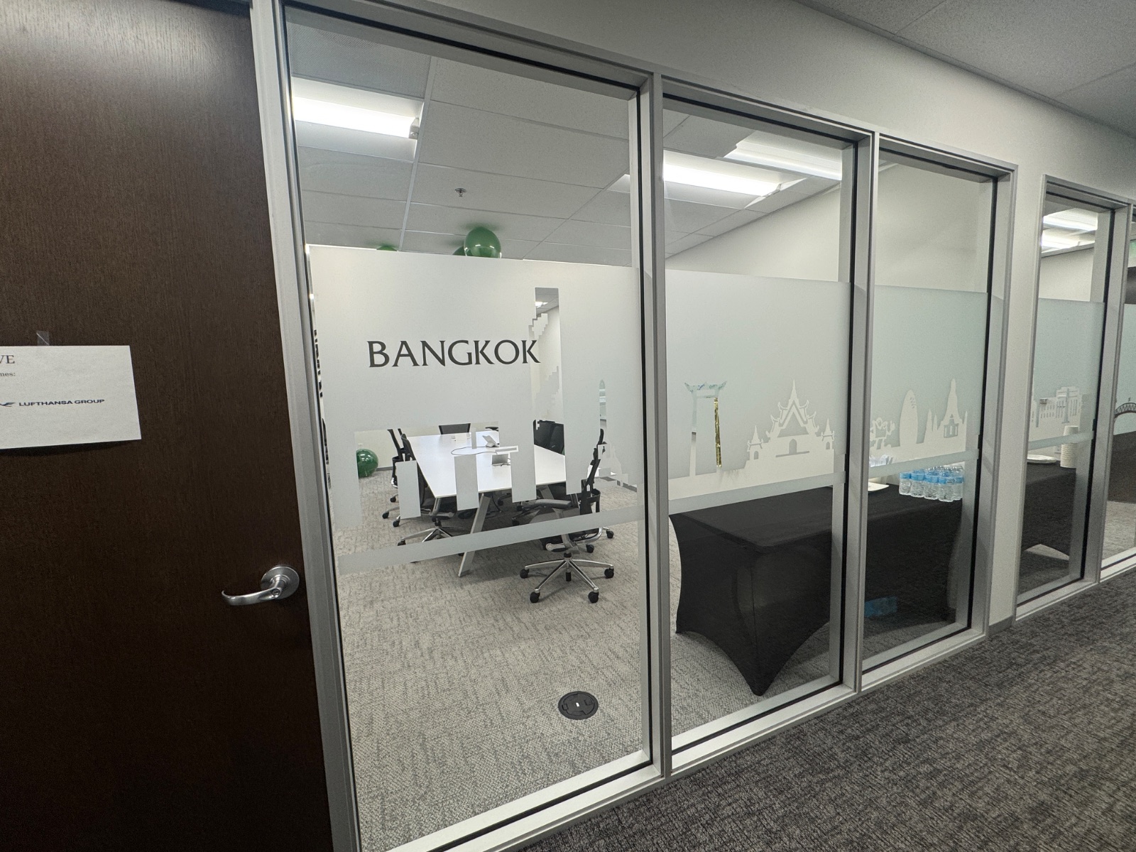 Bangkok meeting room seen from the corridor door side, frosted band and cut-vinyl skyline running the length of the glass