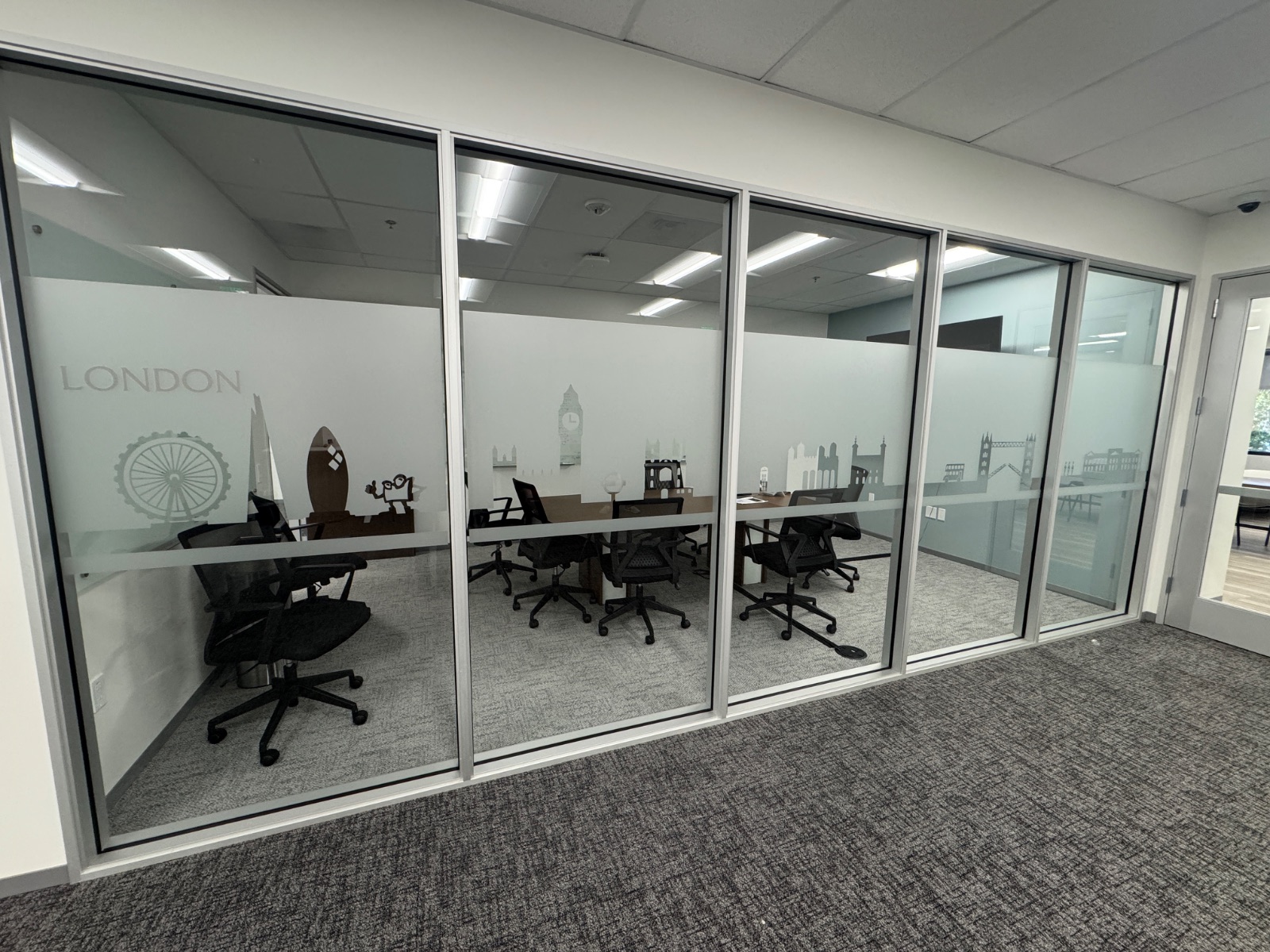 Long run of glass office fronts with continuous frosted privacy film and cut-vinyl London landmark graphics