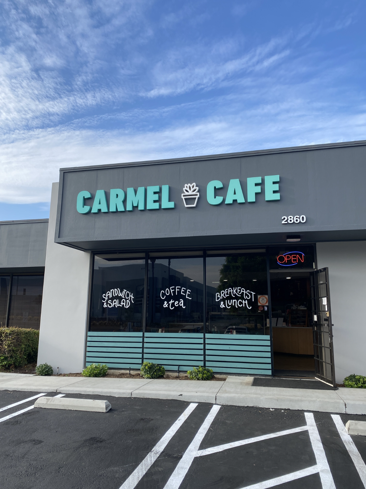 Storefront fascia for Carmel Cafe: teal dimensional letters and a potted-plant logo mounted on a gray fascia band, with hand-lettered window vinyl reading Sandwich & Salad, Coffee & Tea, Breakfast & Lunch